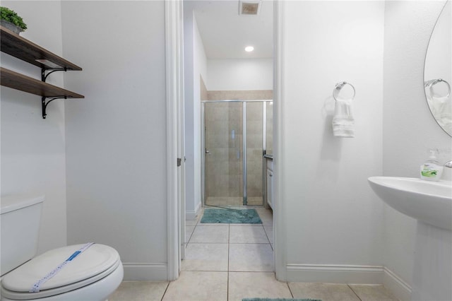 bathroom with tile patterned flooring, a shower with shower door, and toilet