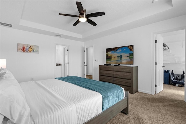 carpeted bedroom featuring ceiling fan and a tray ceiling