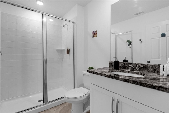 bathroom with toilet, vanity, tile patterned flooring, and a shower with shower door