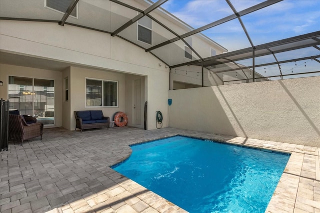 view of pool with a patio, glass enclosure, and an outdoor living space