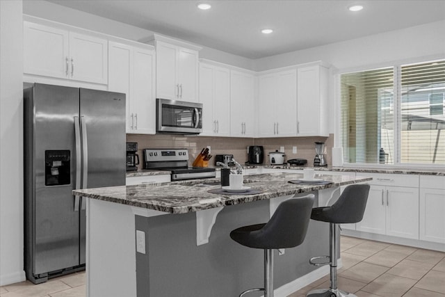 kitchen with appliances with stainless steel finishes, white cabinetry, and stone countertops