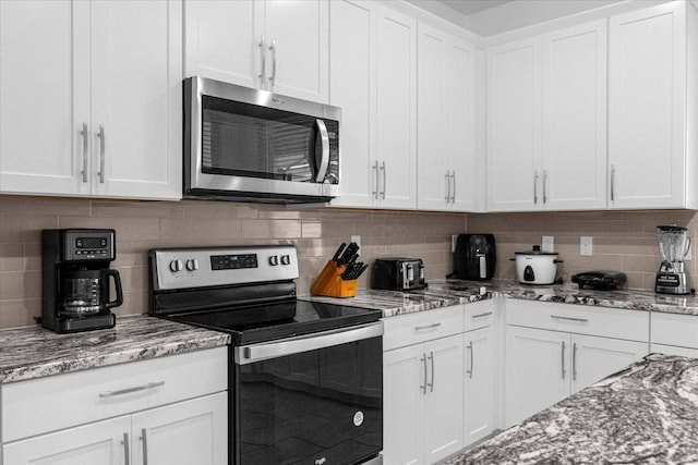 kitchen with white cabinetry, backsplash, light stone counters, and appliances with stainless steel finishes