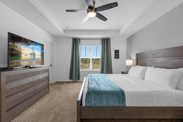 carpeted bedroom featuring ceiling fan, a textured ceiling, and a tray ceiling