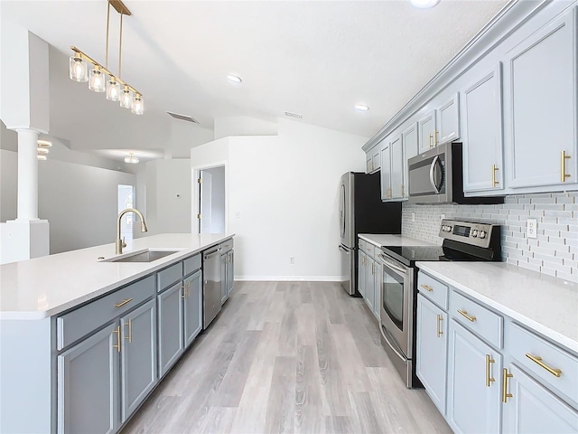 kitchen with appliances with stainless steel finishes, sink, backsplash, vaulted ceiling, and decorative columns