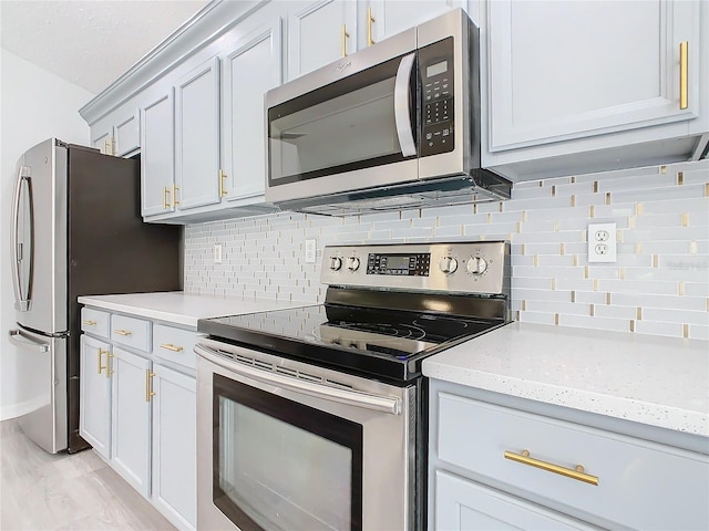 kitchen featuring tasteful backsplash, light stone countertops, appliances with stainless steel finishes, and light hardwood / wood-style floors