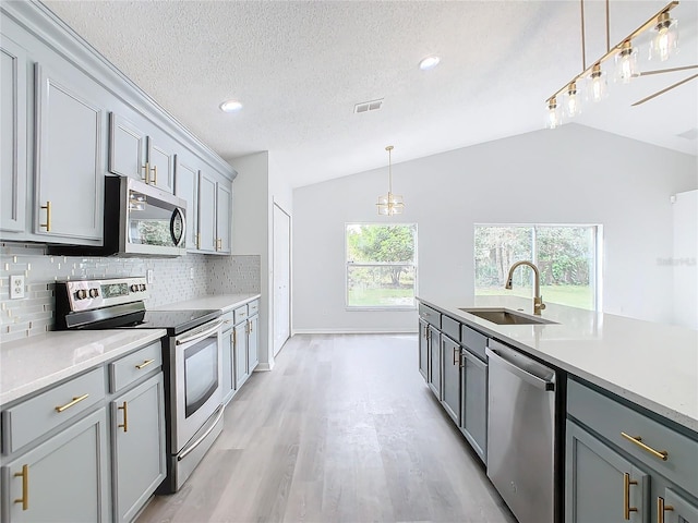 kitchen with lofted ceiling, sink, gray cabinetry, and stainless steel appliances