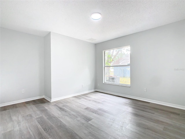 spare room with a textured ceiling and hardwood / wood-style floors