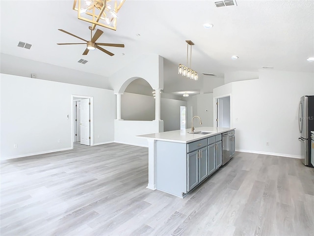 kitchen featuring appliances with stainless steel finishes, decorative light fixtures, an island with sink, sink, and vaulted ceiling