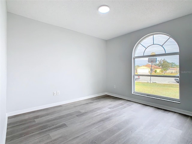 unfurnished room with wood-type flooring and a textured ceiling