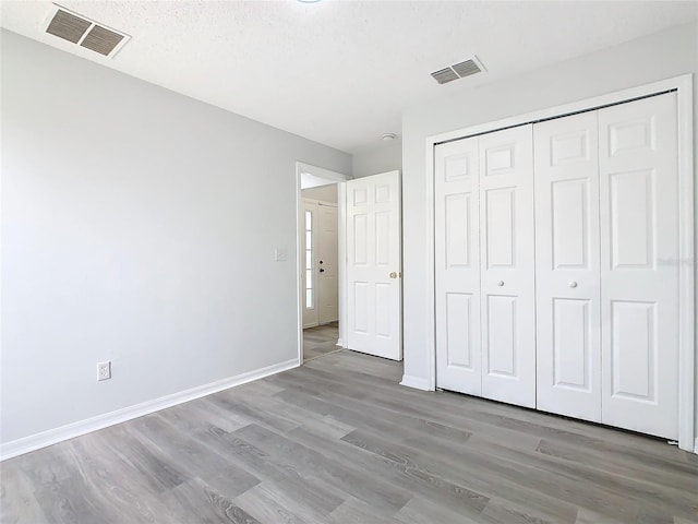 unfurnished bedroom with a textured ceiling, a closet, and wood-type flooring