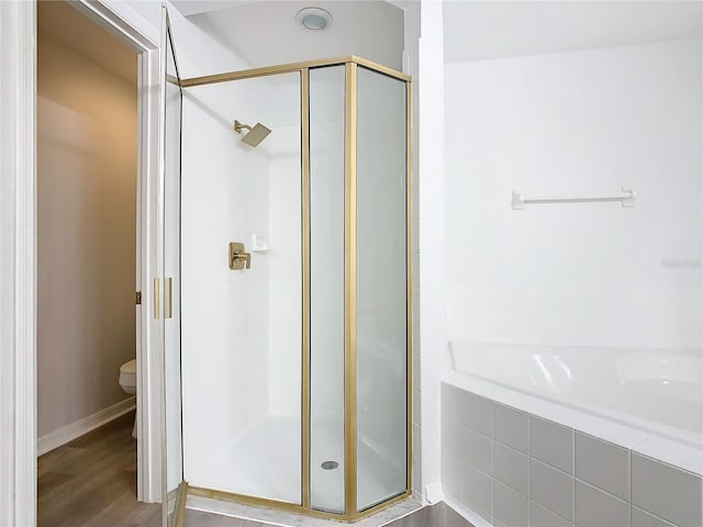 bathroom with toilet, plus walk in shower, and hardwood / wood-style flooring