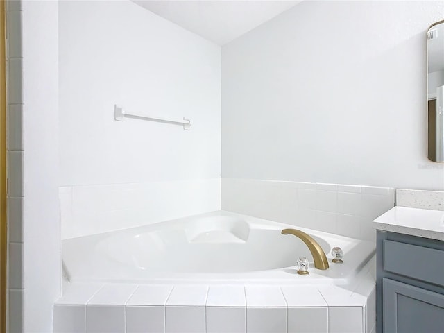 bathroom with vanity and tiled tub