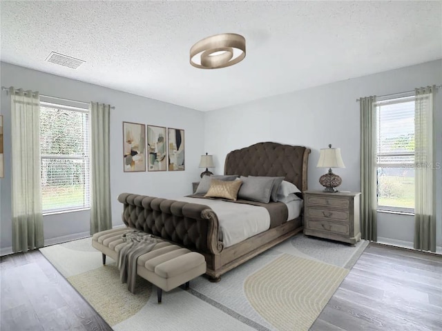 bedroom with multiple windows, a textured ceiling, and hardwood / wood-style floors