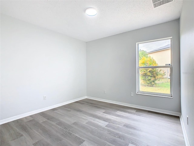 empty room with a textured ceiling and hardwood / wood-style flooring