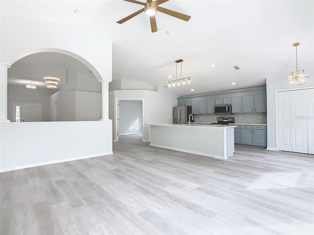 kitchen featuring appliances with stainless steel finishes, backsplash, a kitchen island with sink, lofted ceiling, and pendant lighting