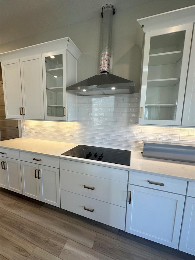 kitchen with white cabinets, wall chimney exhaust hood, backsplash, black electric cooktop, and dark hardwood / wood-style floors