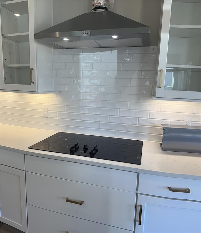 kitchen featuring black electric cooktop, white cabinets, ventilation hood, and decorative backsplash