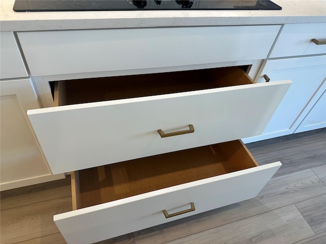 room details with white cabinets and hardwood / wood-style flooring