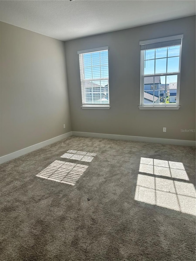 unfurnished room featuring dark carpet and plenty of natural light