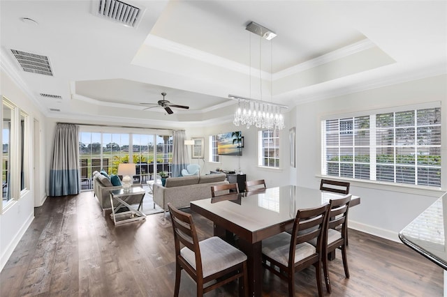 dining area featuring ceiling fan, dark wood-type flooring, a tray ceiling, and crown molding