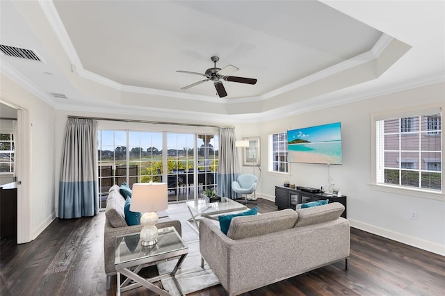 living room with ceiling fan, ornamental molding, dark wood-type flooring, and a tray ceiling