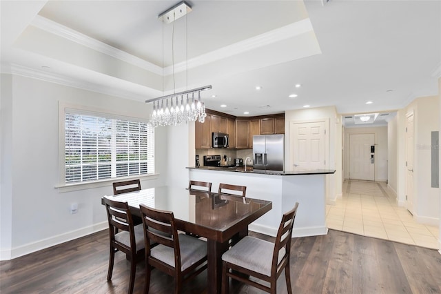 dining space with a tray ceiling, dark hardwood / wood-style floors, and ornamental molding