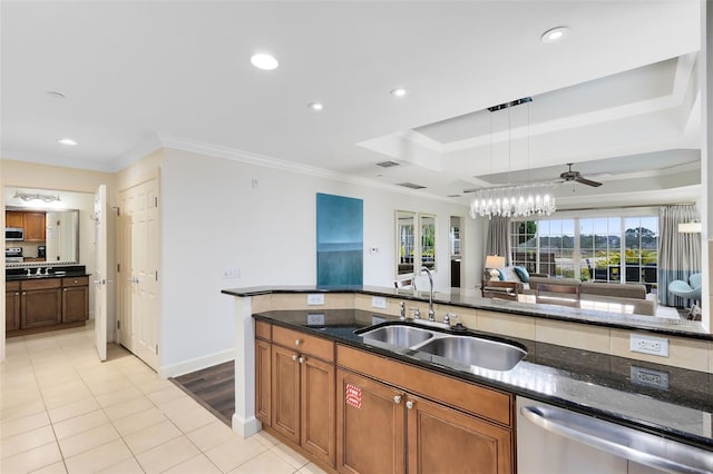 kitchen featuring crown molding, appliances with stainless steel finishes, sink, dark stone countertops, and a tray ceiling