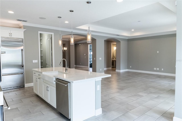 kitchen with crown molding, white cabinetry, light stone counters, a center island with sink, and stainless steel appliances