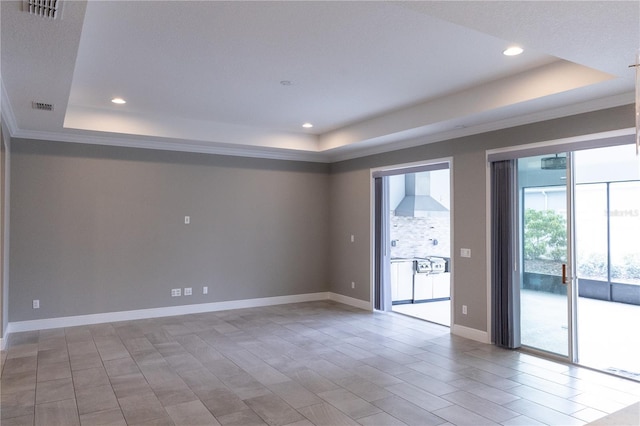 empty room featuring a raised ceiling and ornamental molding