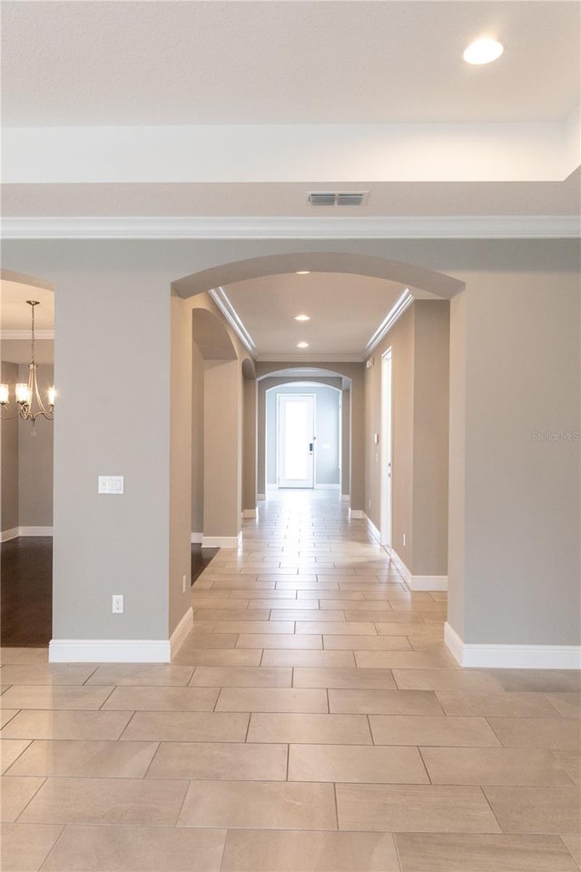 hallway with a notable chandelier and crown molding