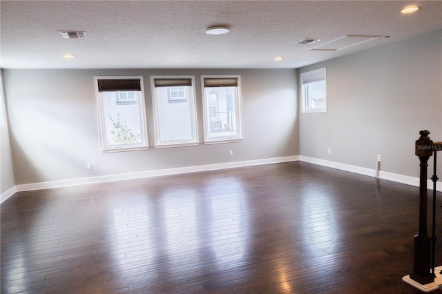 spare room featuring dark wood-type flooring and a textured ceiling