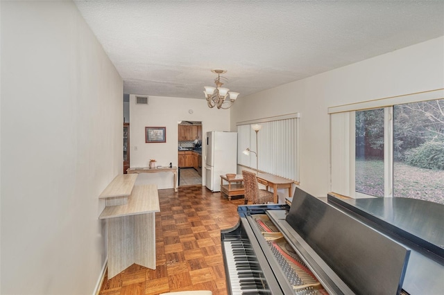 misc room with dark parquet flooring, a textured ceiling, and a chandelier