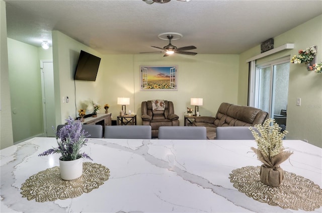 living room with ceiling fan and a textured ceiling