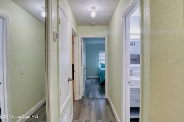 corridor featuring wood-type flooring and a textured ceiling