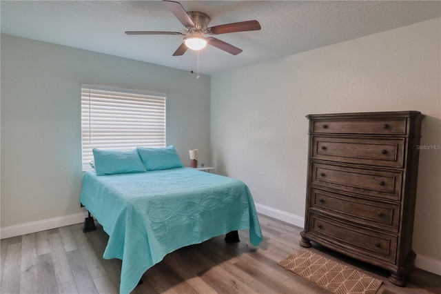 bedroom with ceiling fan, light hardwood / wood-style flooring, and a textured ceiling