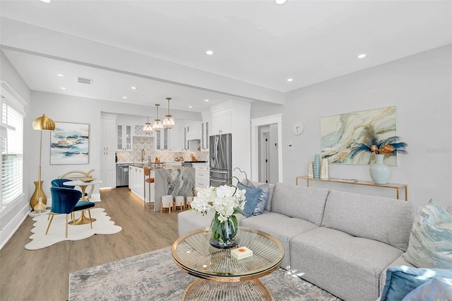 living room featuring sink and light hardwood / wood-style flooring