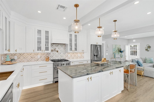 kitchen with white cabinetry, a center island, dark stone counters, premium range hood, and appliances with stainless steel finishes