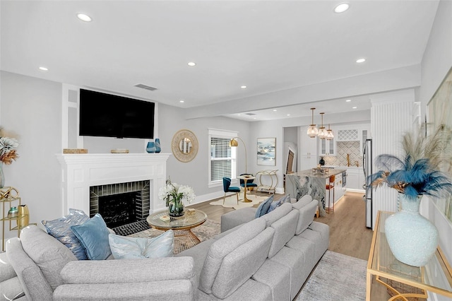 living room with light hardwood / wood-style floors and a brick fireplace