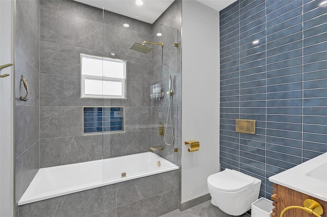 full bathroom featuring toilet, vanity, tile walls, and tiled shower / bath