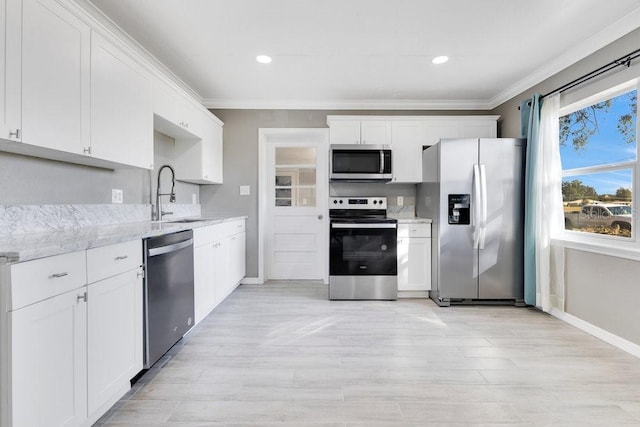 kitchen featuring white cabinetry, sink, light stone countertops, appliances with stainless steel finishes, and ornamental molding