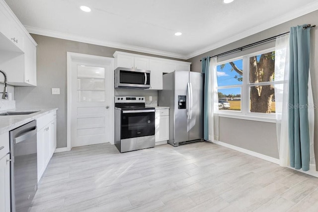 kitchen with white cabinetry, sink, stainless steel appliances, and ornamental molding