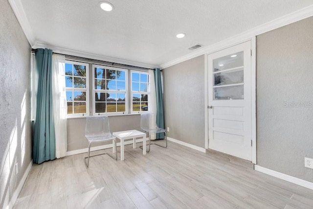 living area with light hardwood / wood-style floors and ornamental molding