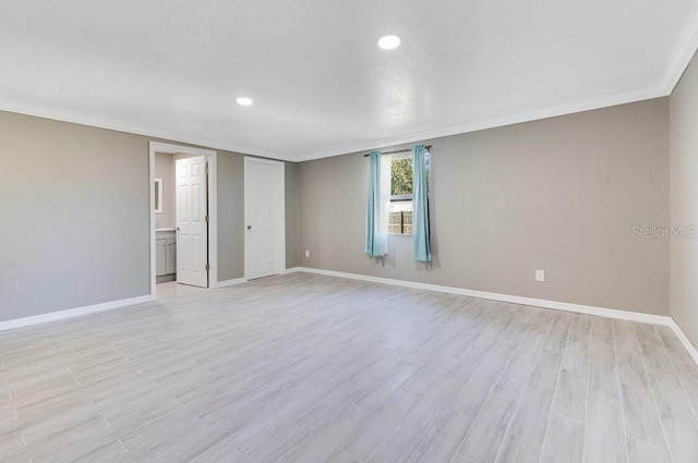 empty room with crown molding and light hardwood / wood-style floors