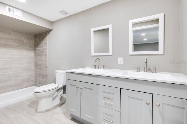 bathroom featuring vanity, toilet, and a tile shower