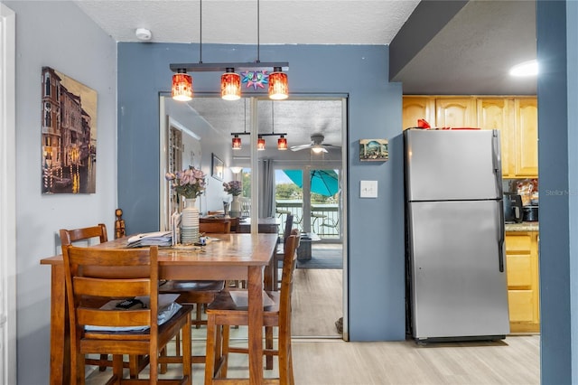 dining area with a textured ceiling, light hardwood / wood-style flooring, and ceiling fan