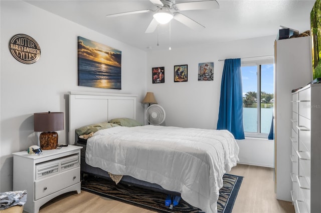 bedroom with ceiling fan, a water view, and light hardwood / wood-style floors