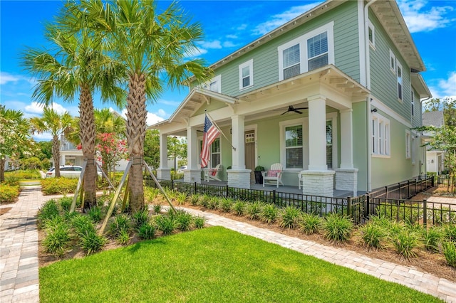 view of front facade with ceiling fan, covered porch, and a front lawn