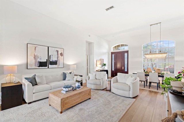 living room with light hardwood / wood-style floors and a notable chandelier