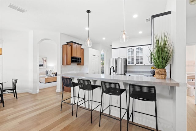 kitchen with stainless steel refrigerator, a kitchen breakfast bar, pendant lighting, decorative backsplash, and white cabinets