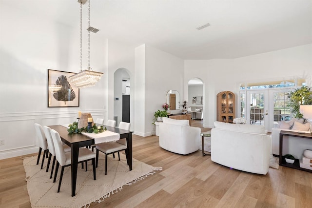 dining room with french doors, light wood-type flooring, and an inviting chandelier